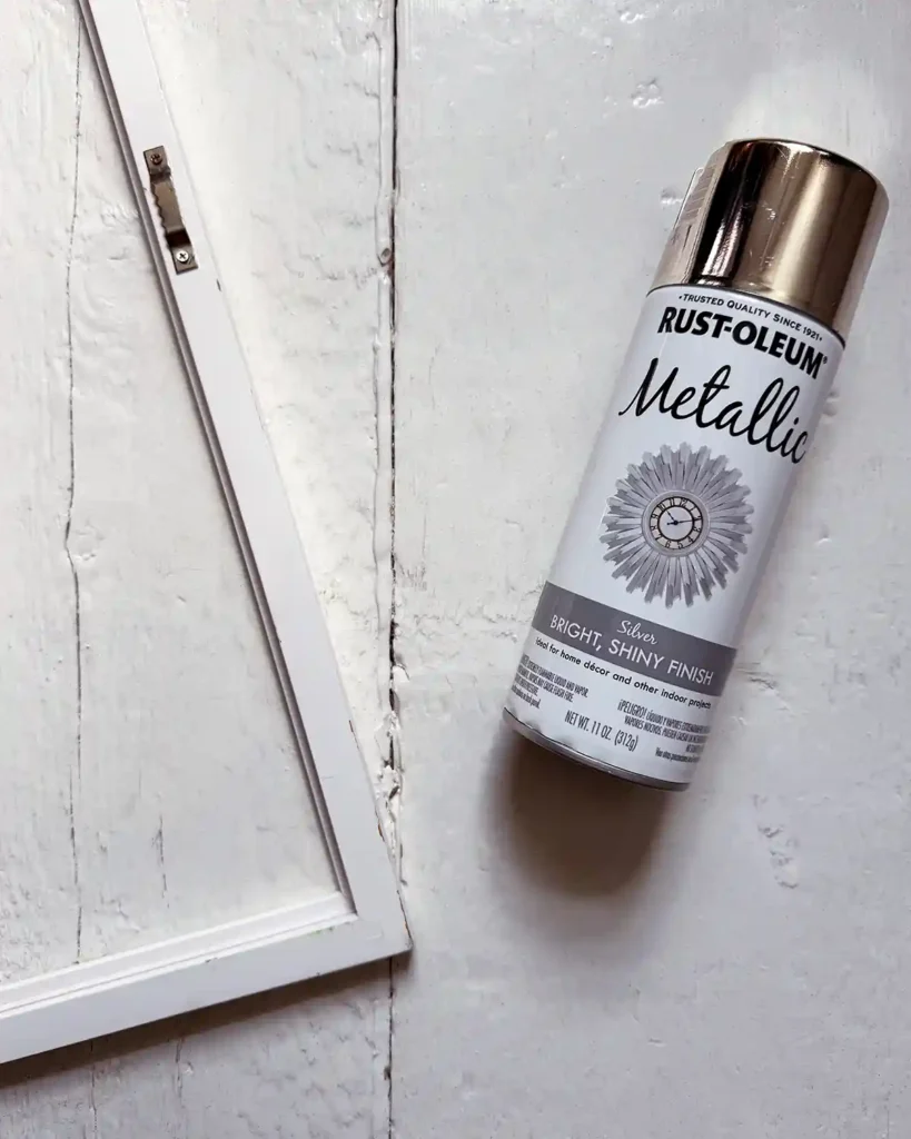 A can of Rustoleum metallic spray paint sitting next to a white picture frame before spray painting