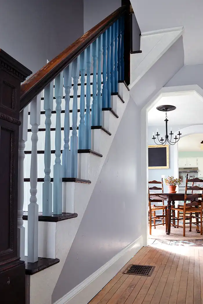 An unfinished attic turned into a finished attic walk-in closet with v-groove planks painted white and hanging rod for clothes under the eaves