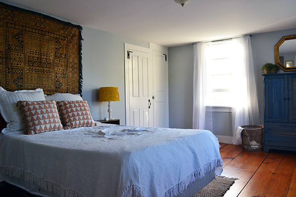 Guest bedroom with tapestry hanging behind the bed