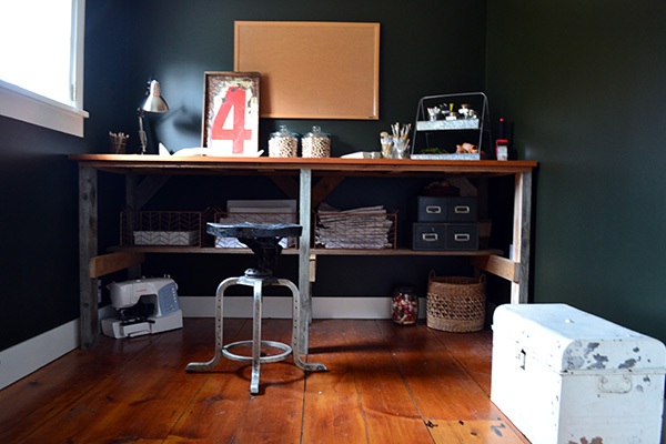 Black craft room with rustic wood desk and wide pine floors