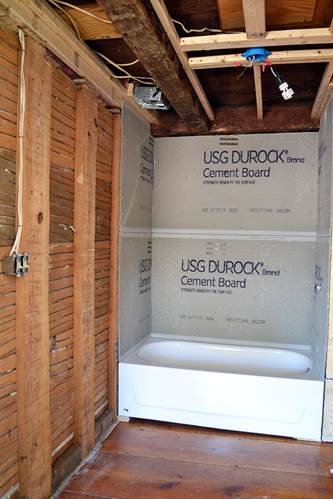 Gutted bathroom with tub and durock installed and plumbing and electrical roughed in