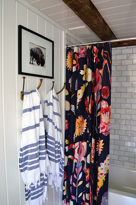 Bathroom renovation with marble subway tile, planked walls, and old wood beams.