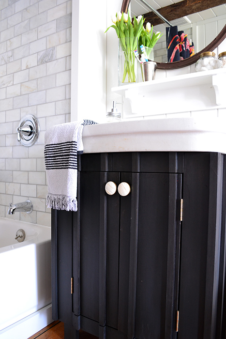 During this bathroom renovation, a sink base was chalk painted in Annie Sloan's graphite, finished with a dark wax, and accented with round white and gold knobs from Hobby Lobby.