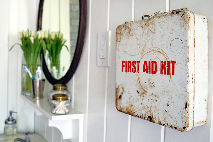 A metal, vintage first aid cabinet hangs above the toilet in this farmhouse bathroom.