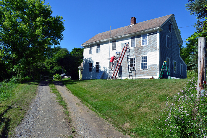 Scraping and painting the exterior clapboards of an old colonial farmhouse