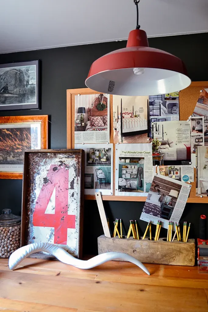 A farmhouse pendant spray painted red hangs over a rustic craft room table