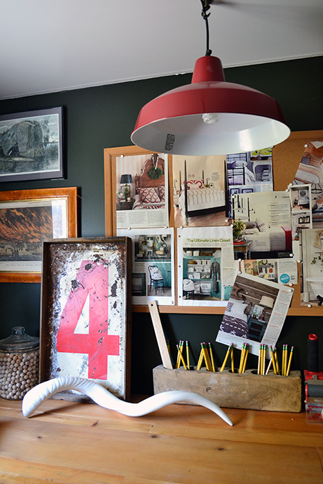 A red farmhouse light fixture hanging over a rustic wood work bench