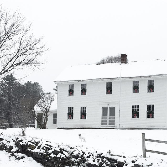 A white colonial farmhouse with Christmas wreaths on the windows for simple Christmas decor