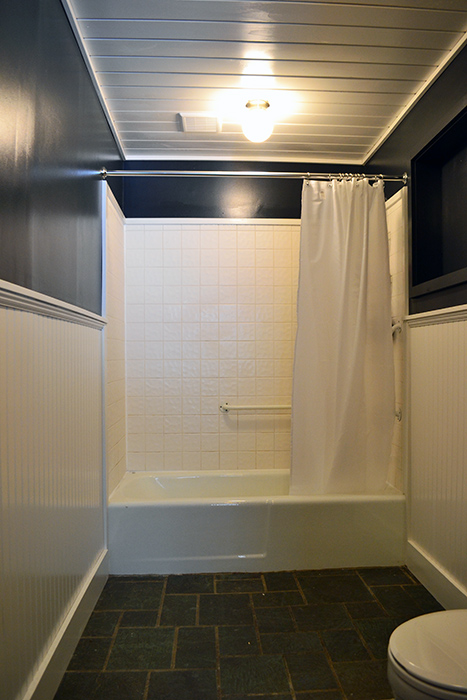 First floor bathroom renovation progress with planked ceiling, beadboard walls, and slate tile