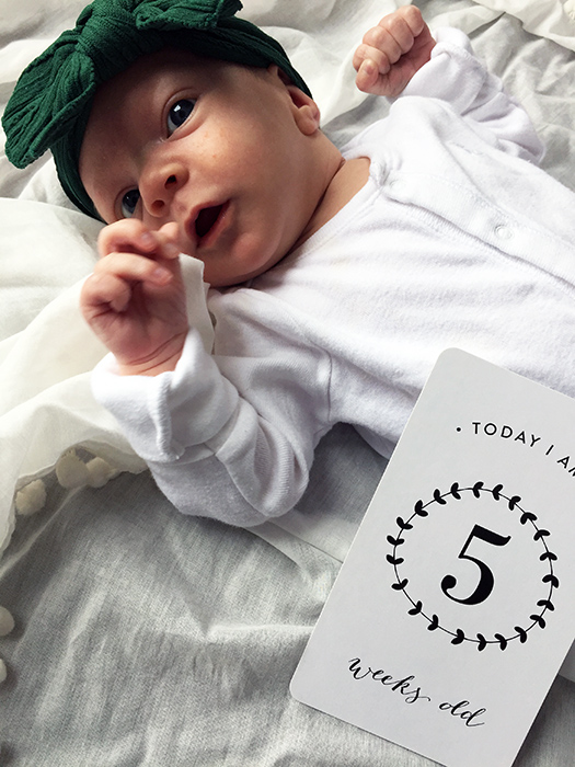 Newborn baby at five weeks old with Little Milestones cards