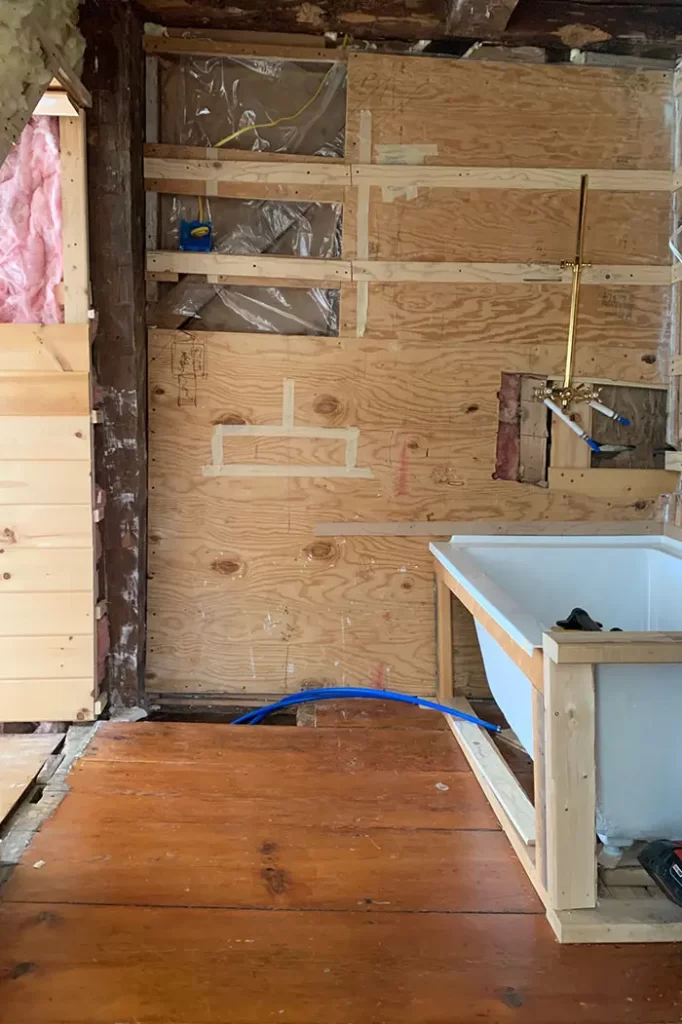 Bathroom renovation progress with a view toward the attic door and tub