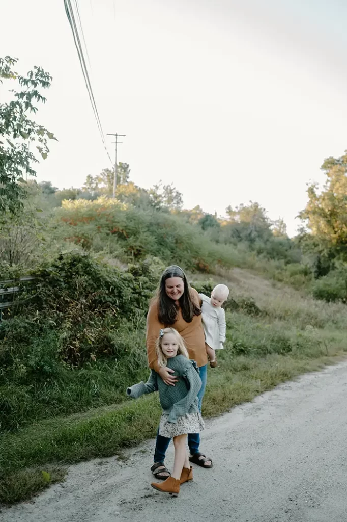 Family photo with mom and two little girls on a dirt road in the country