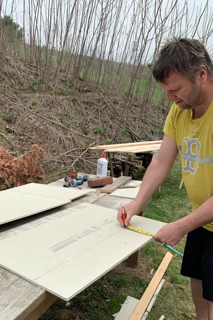 Using a tape measure and sharpie to measure and mark cement board for cutting