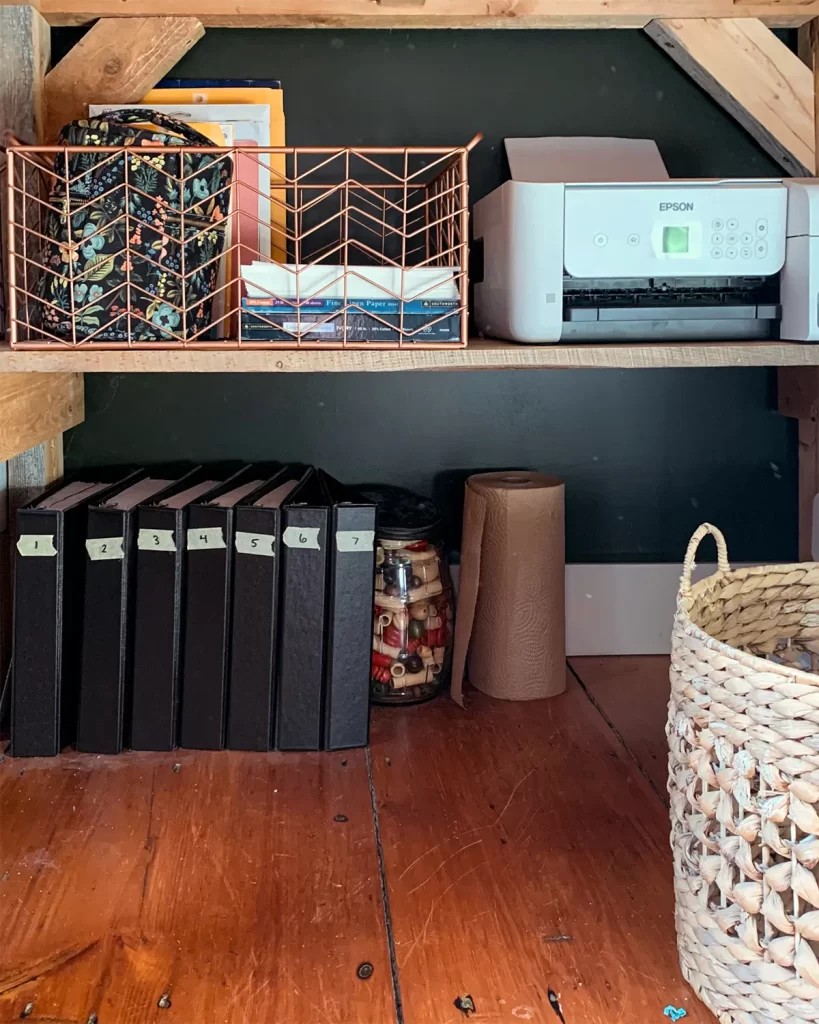 Organizing magazine clippings in design binders underneath a craft room desk