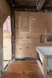 Small bathroom renovation progress with a door to attic closet