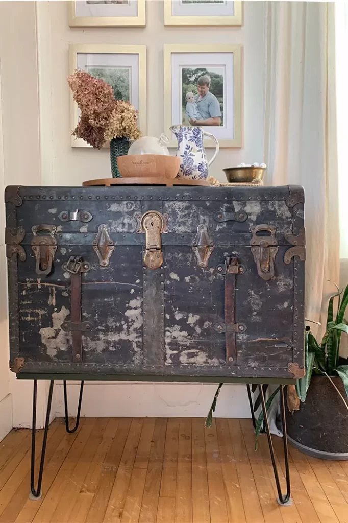 Vintage trunk turned into a console table for storing puzzles, black hairpin legs added to trunk, essential oil diffuser station on top of trunk