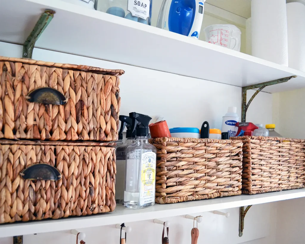 Woven baskets on open laundry room shelves to store cleaning products, dish rags, lightbulbs, and more