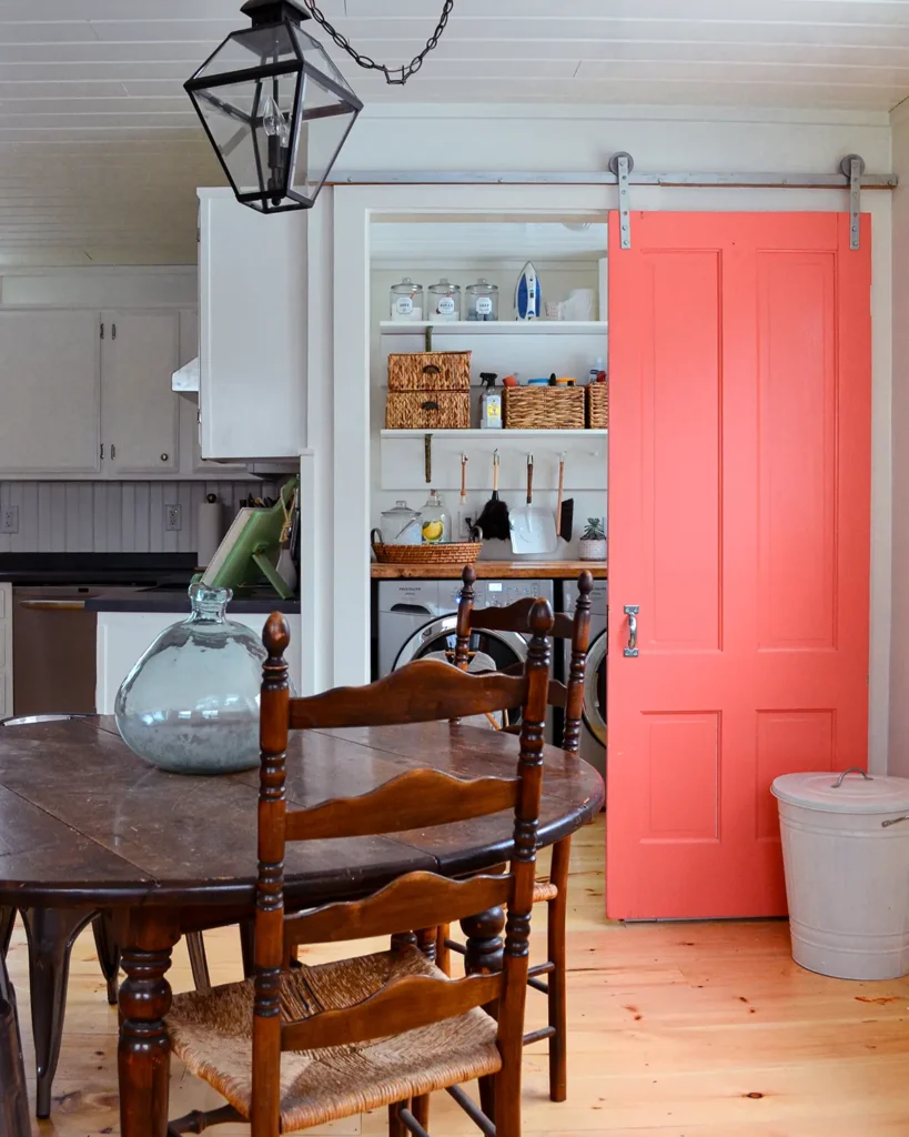 Small laundry room makeover including building DIY shelves, planking a ceiling, and repurposing an old door into a pink sliding barn door