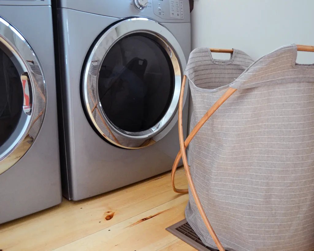 A three compartment laundry hamper from West Elm helps sort dirty clothes in a small laundry room