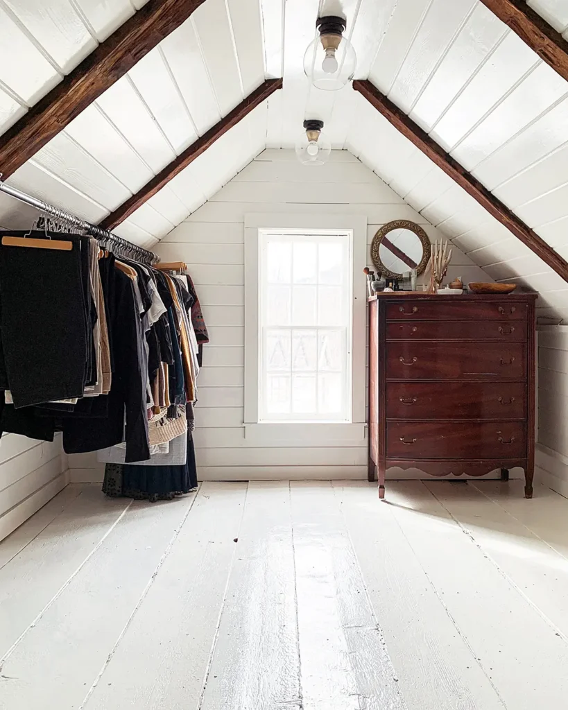 An unfinished attic turned into a large walk-in closet with white painted flooring, exposed beams, shiplap ceiling, and a vintage dresser