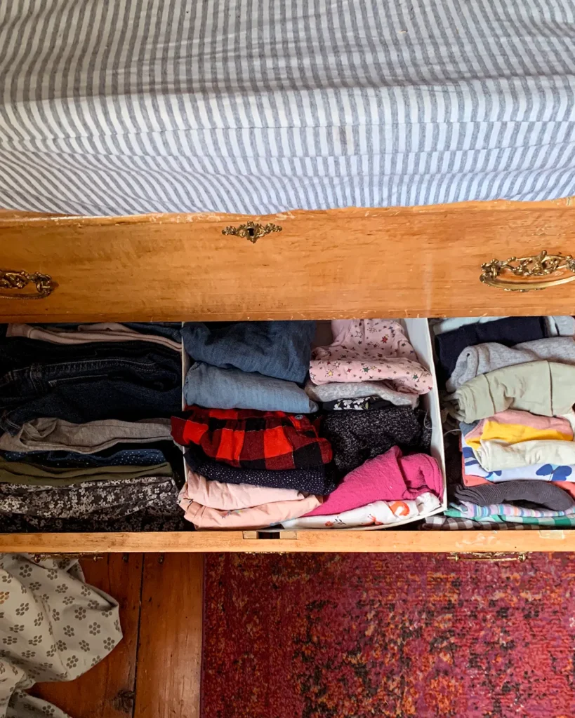 Baby clothes organized in a vintage dresser using drawer dividers to keep pants, long-sleeve shirts, and sort-sleeve shirts separated