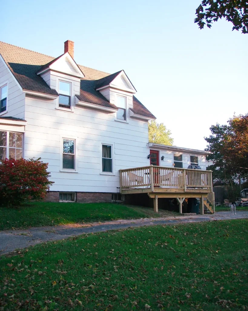 Building a small deck on the side of a white home in the narrow space between the house and the driveway