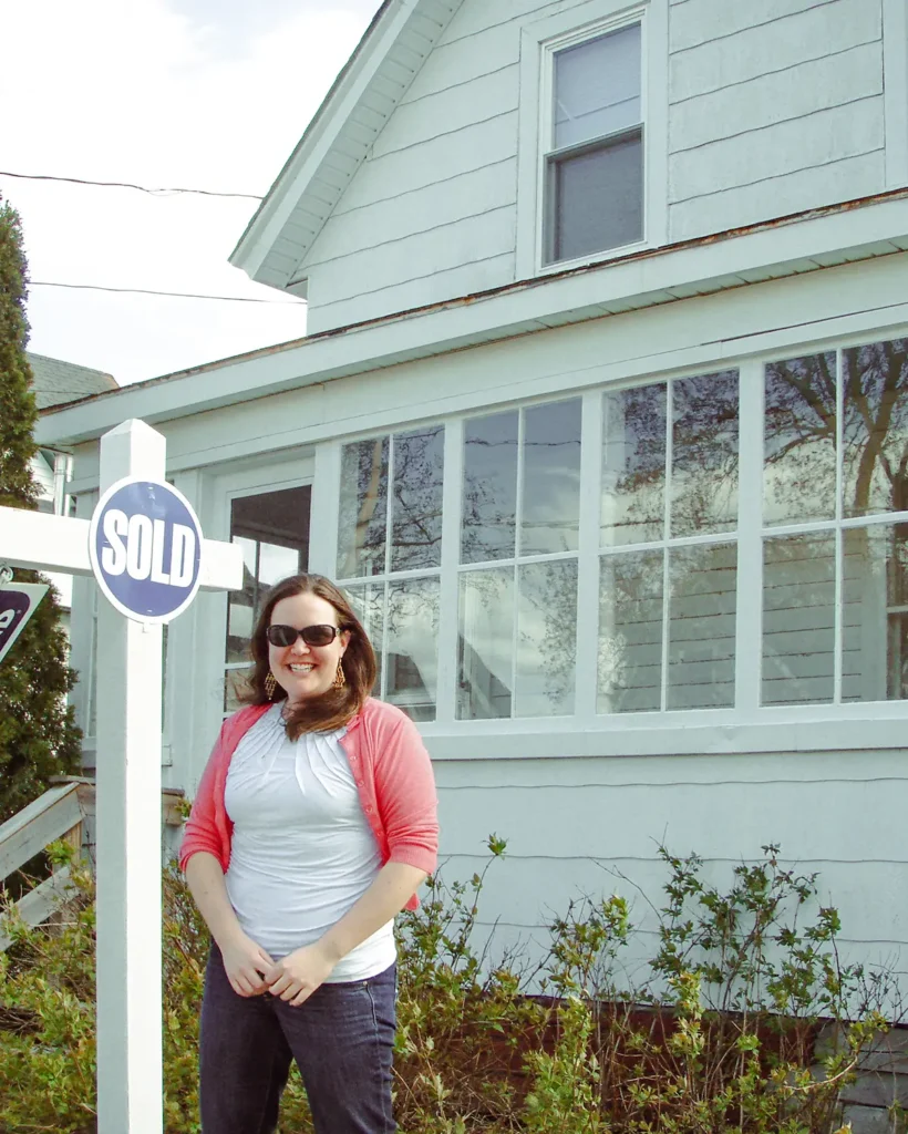 Young woman buying her first home standing in front of the house on closing day in the spring