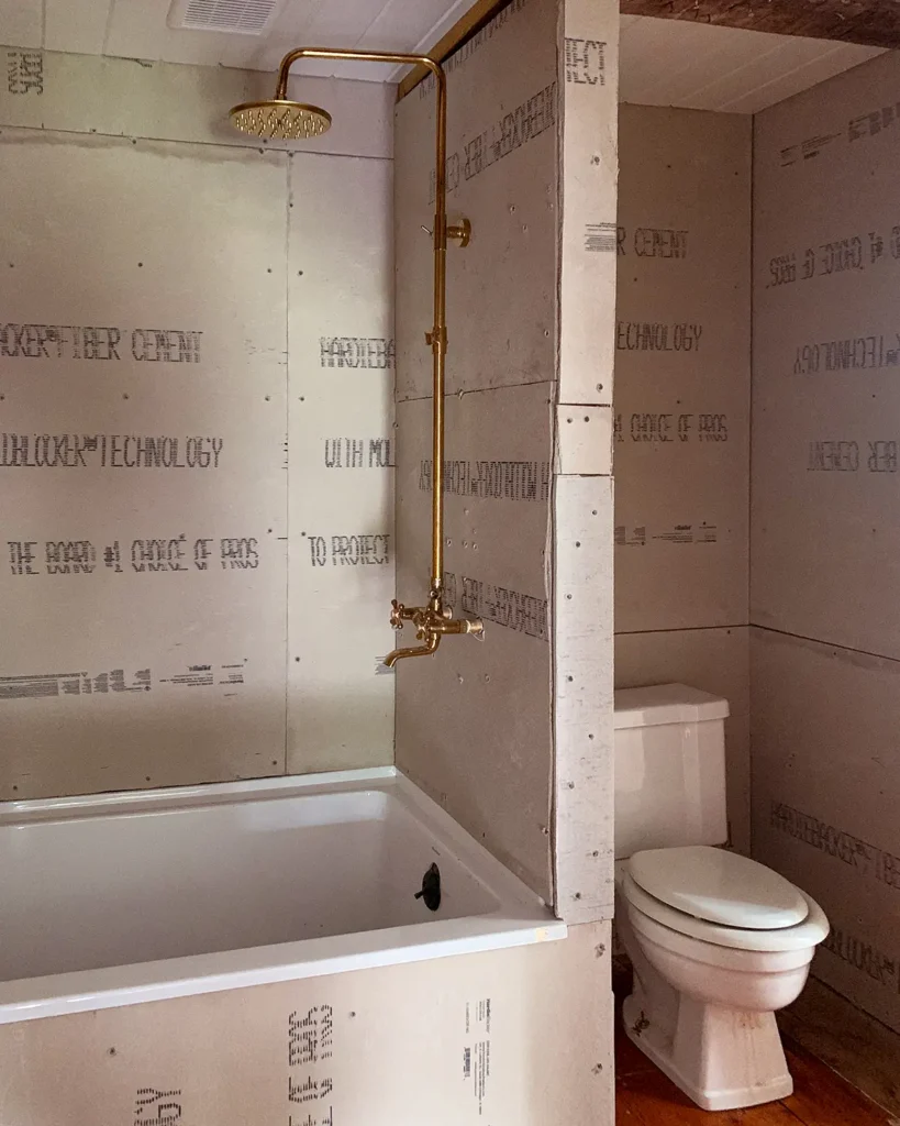 Building a DIY bathroom wall to enclose a bathtub and shower surround and create a toilet nook in a small bathroom