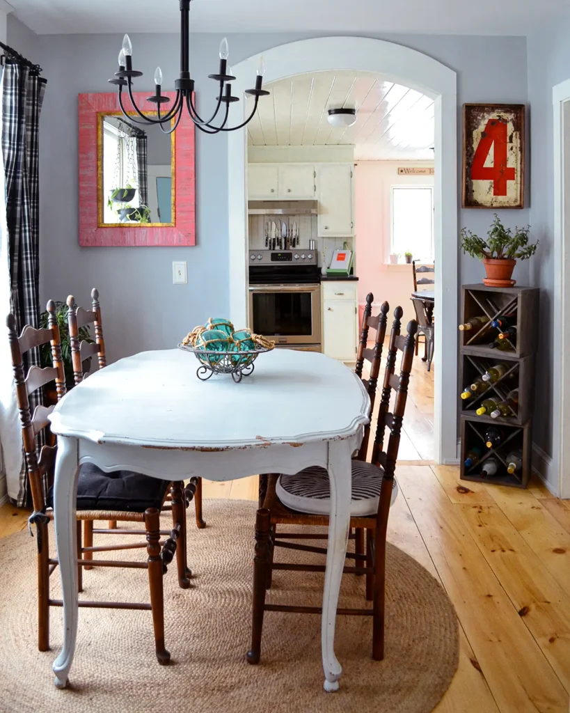 Dining room with wide pine floors, vintage furniture, and an arched doorway into a kitchen