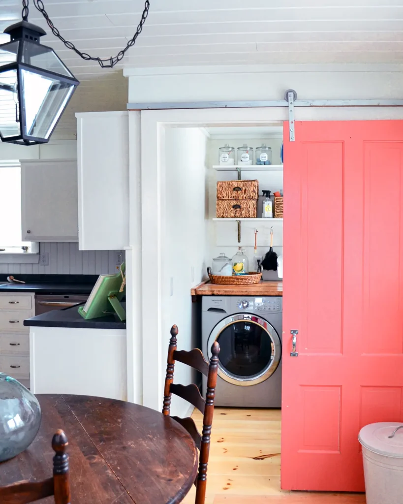 A pink sliding barn door for a laundry room on a DIY barn door track