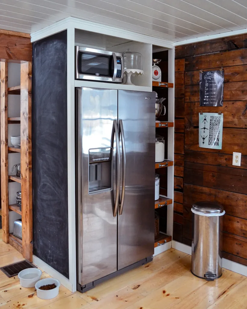 Whirlpool Gold refrigerator next to a rustic wood wall in a kitchen with pine floors