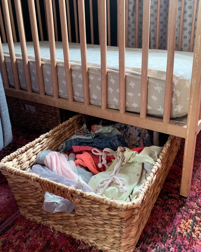 Baby clothes stored in a basket underneath a crib is a favorite storage idea for a small nursery