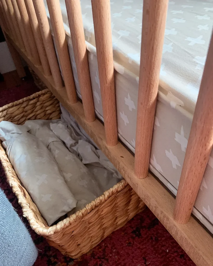 Storing crib sheets and extra blankets in a basket underneath a crib is an easy storage idea for a small nursery