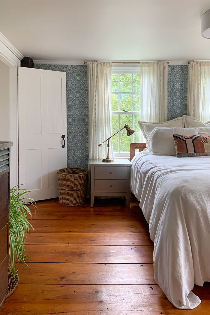 An unfinished attic turned into a finished attic walk-in closet with v-groove planks painted white and hanging rod for clothes under the eaves