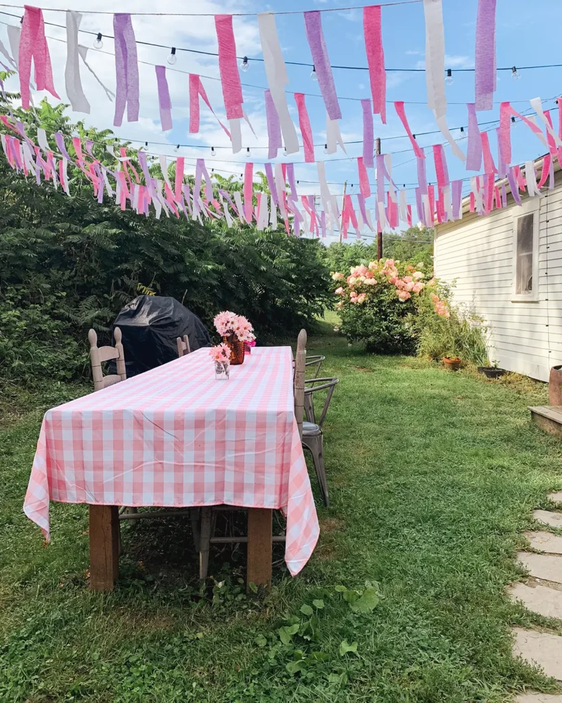 Hanging DIY crepe paper bunting above an outdoor dining table for a little girl's birthday party