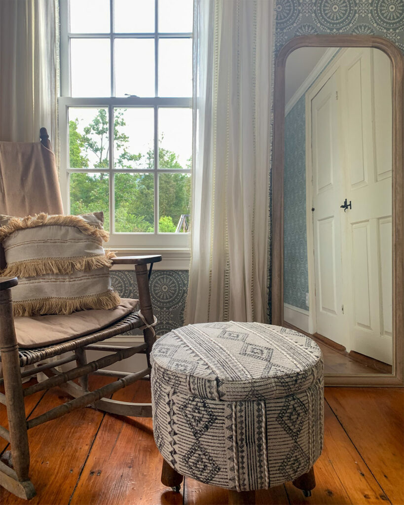 Vintage rocker in a bedroom next to a full length mirror and fabric footstool