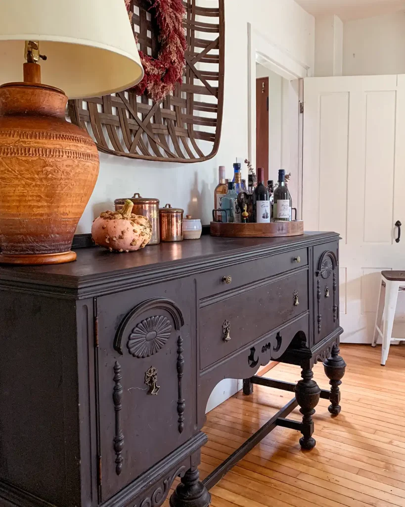 Vintage buffet in dining room refinished wood with painted finish, Annie Sloan chalk paint in Graphite color, large vintage lamp on top and tobacco basket