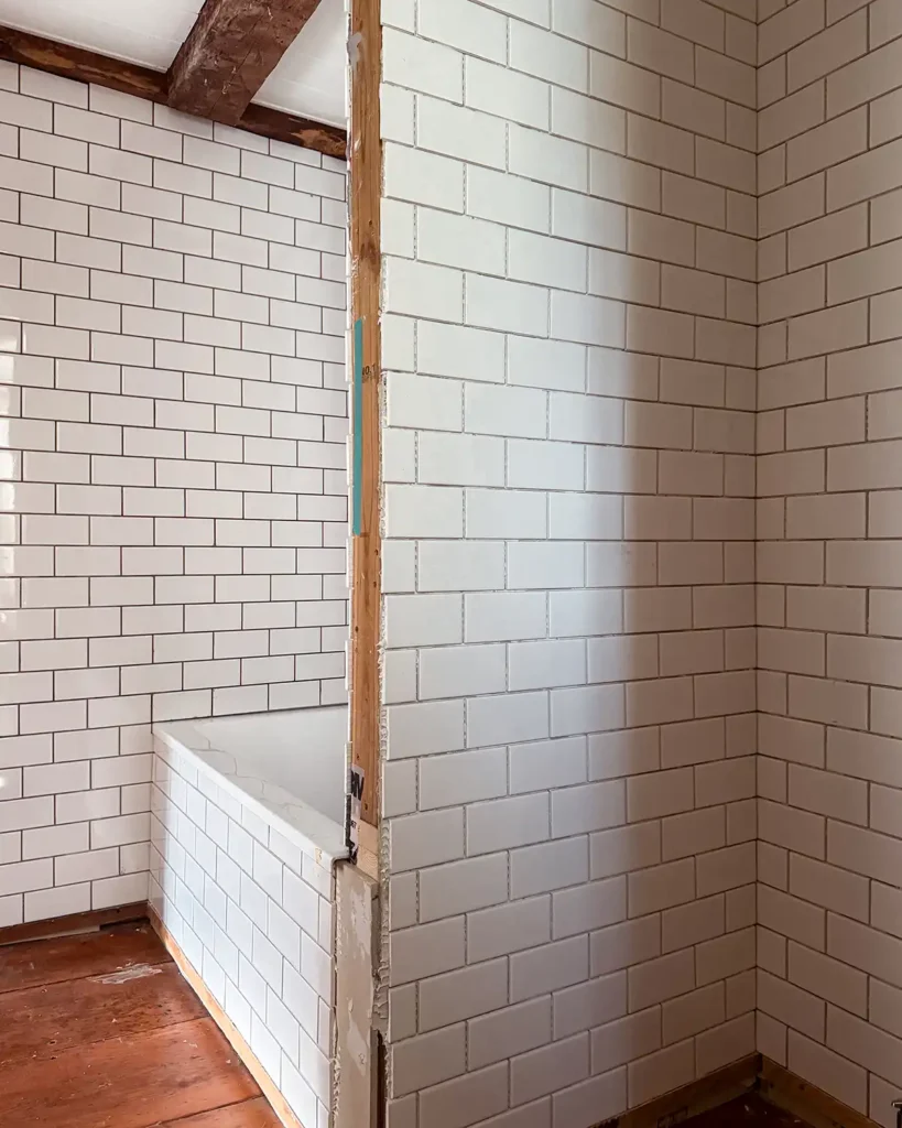 Bathroom renovation progress with most of the walls covered with subway tile but ungrouted