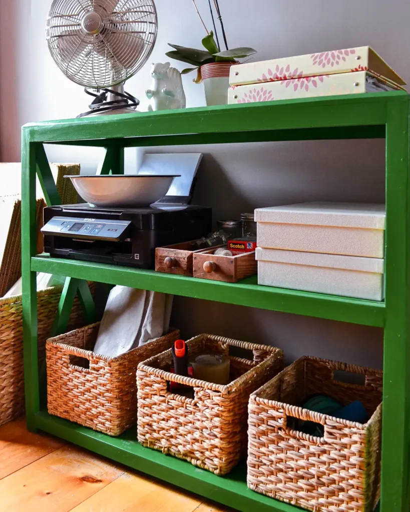 Bold color green painted bookcase in a home office and work room with vintage style fan, printer, and organized paper goods