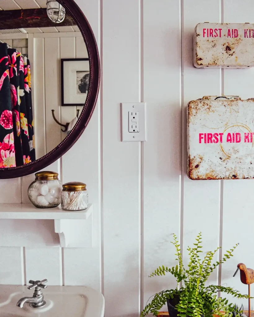 A complete bathroom renovation with shiplap walls, vintage first aid boxes and mirror, and bold shower curtain from Anthropologie