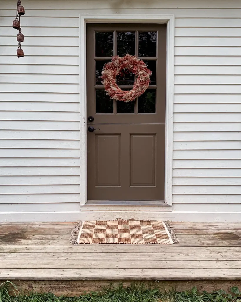 Fall wreath on a door and an outdoor rug on a fall front porch