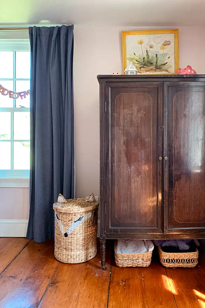 An unfinished attic turned into a finished attic walk-in closet with v-groove planks painted white and hanging rod for clothes under the eaves