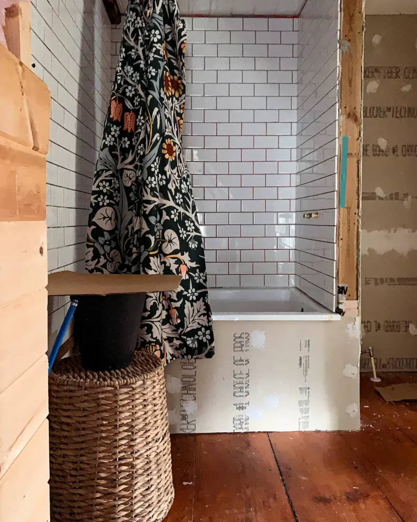 Testing the cardboard vanity top size mockup in a small bathroom with a floral shower curtain and white subway tile