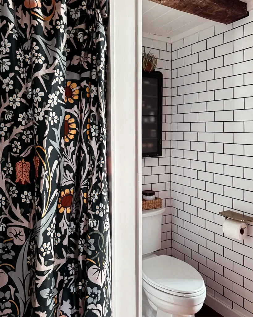 House of Hackney floral shower curtain from Anthropologie against a white subway tile bathroom with black grout