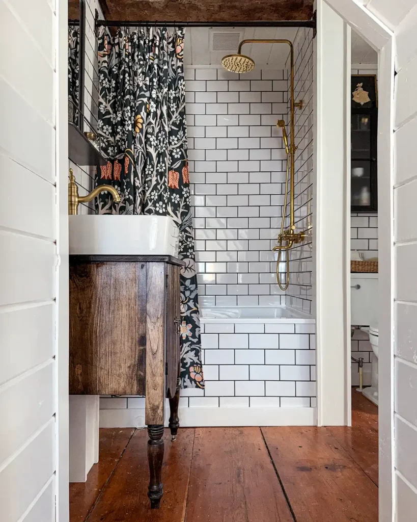 Bathroom renovation DIY project reveal. White subway tiled shower and walls with black grout. Wood vanity with white vessel sink. Gold shower hardware.