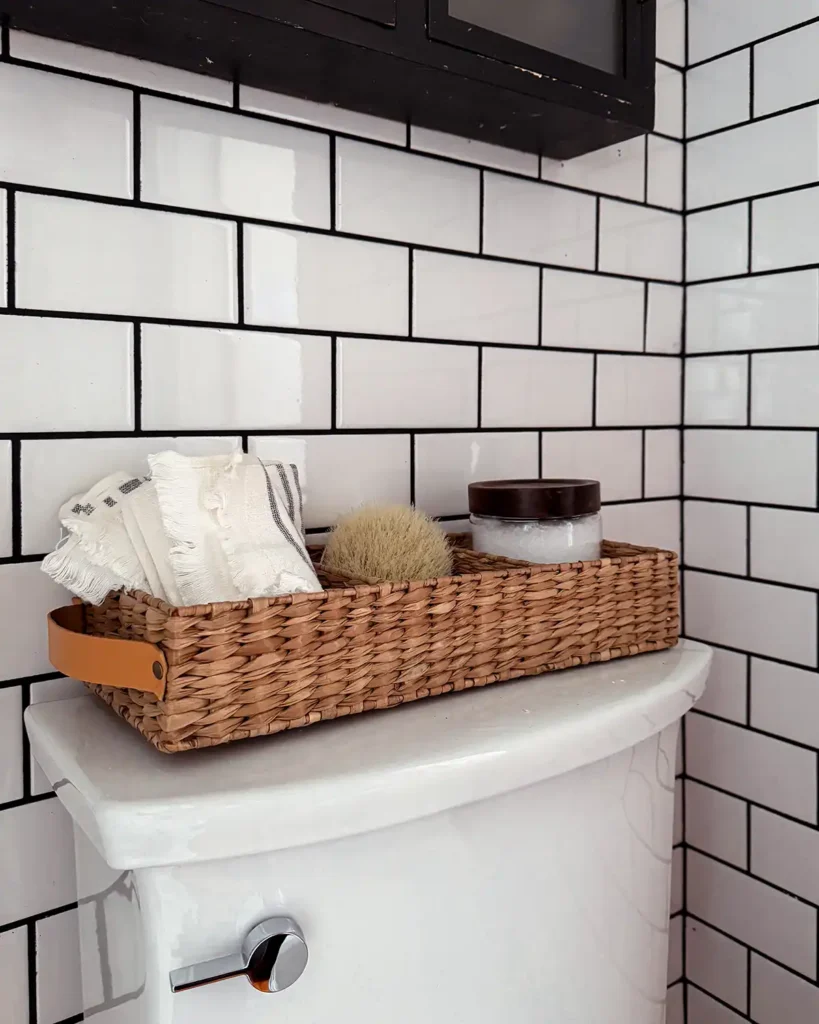 Toilet tank basket for storage from Target's Threshold line, filled with washcloths, a dry brush, and Epsom salts in a white subway tiled bathroom