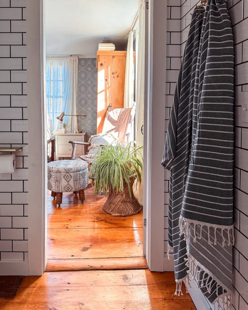 Turkish bath towels from Olive and Linen hanging from gold hooks in a bathroom, looking into the primary bedroom