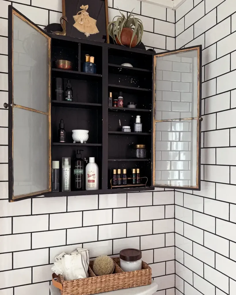 Black vintage cabinet hung on bathroom wall filled with personal care products and styled with vintage accessories