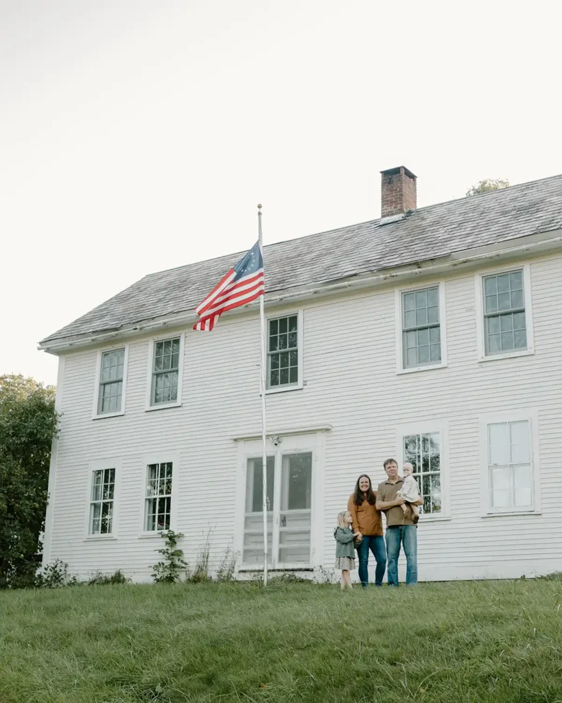 A family photo in front of a white early colonial home from 1781 