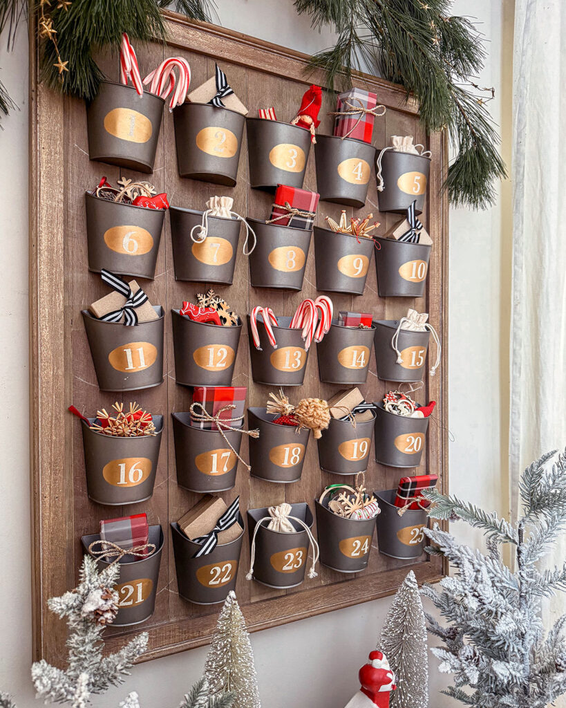 Advent calendar filled with sweet treats, activities, and ornaments to hang on the tree. Wood advent calendar with galvanized buckets for items.